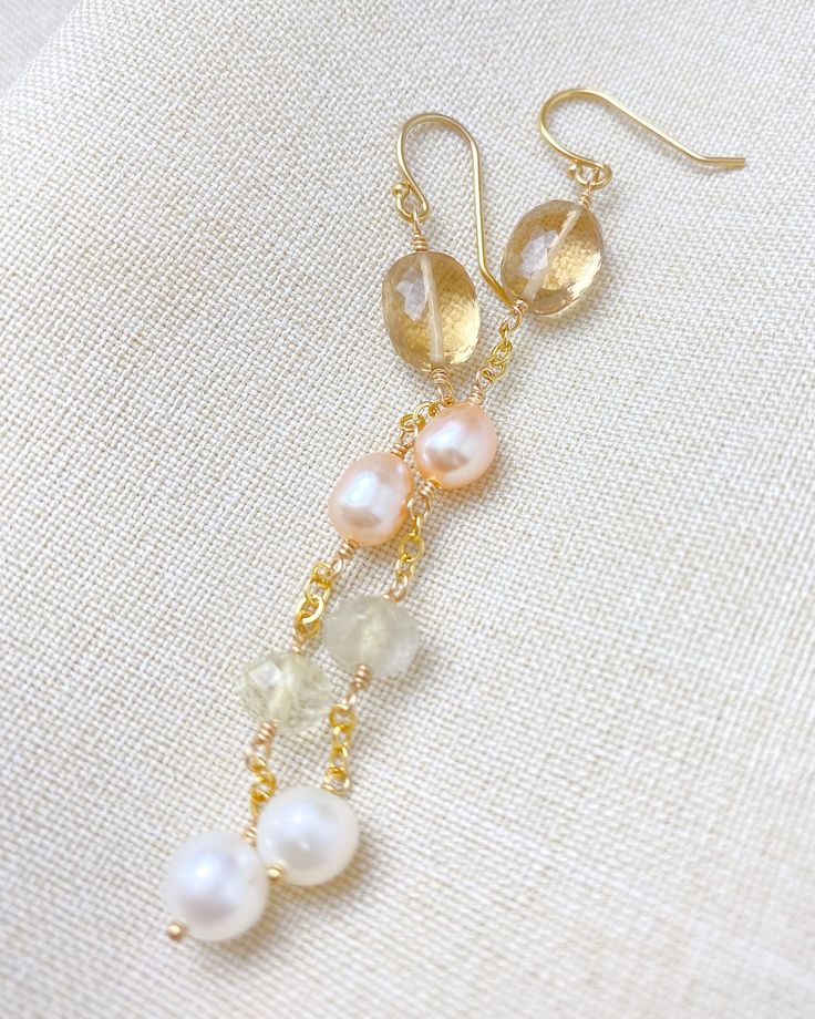 Add some understated elegance to your style with our golden gemstone and pearl earrings. These long linear earrings feature beautiful golden quartz gems paired with soft pink and white freshwater pearls. They are handcrafted in 14K gold-fill for a timeless and unique look. Clear earbacks are included for a secure fit. Length: 2.75 inches Materials: 14K gold fill, champagne quartz, golden rutilated quartz, cultured freshwater pearls Gift box included. Gold Natural Stones Drop Pearl Earrings, Gold Pearl Earrings With Natural Stones, Elegant Gold Linear Earrings With Natural Stones, Gold Dangle Pearl Earrings With Natural Stones, Gold Briolette Pearl Gemstone Earrings, Linear Earrings, Pink Pearl Earrings, Golden Quartz, Pearl Gifts