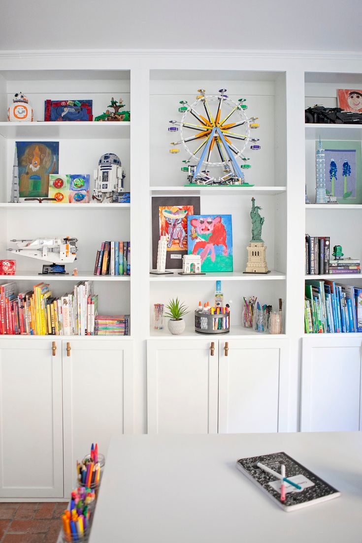 there are many bookshelves in the room with pictures on them and crayons