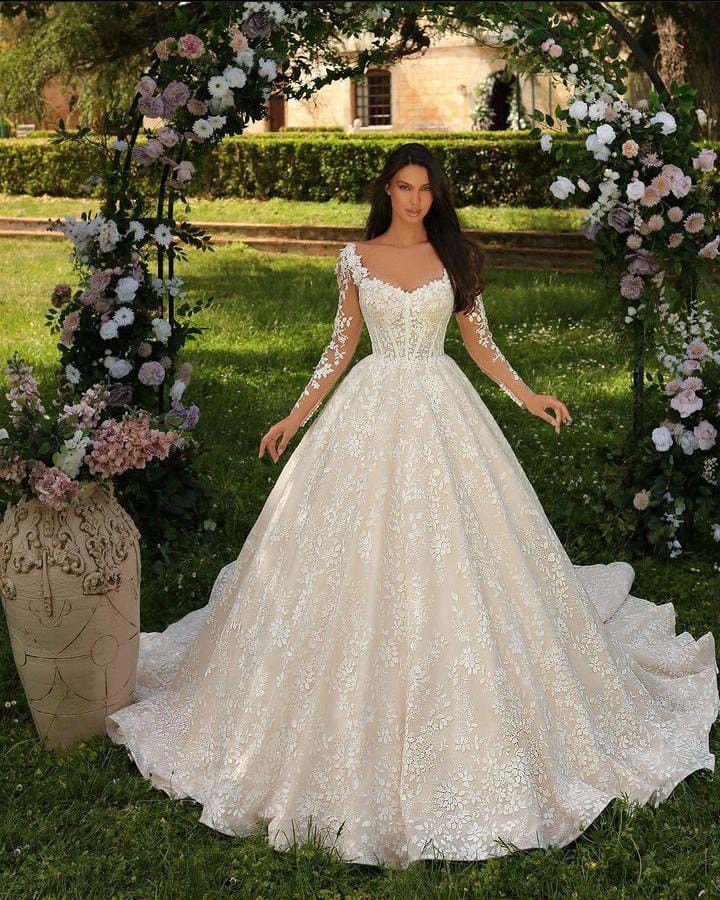 a woman wearing a wedding dress standing in front of an arch with flowers on it