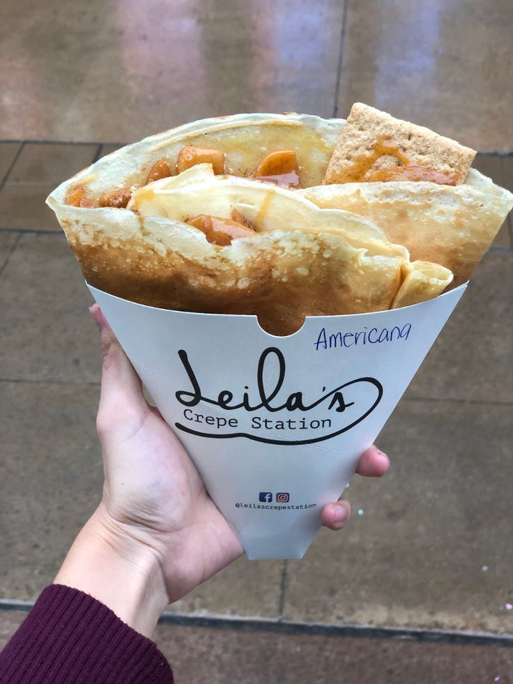 a person holding up a cup filled with food