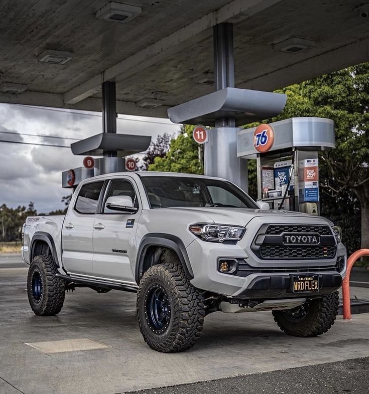 a white toyota truck parked at a gas station