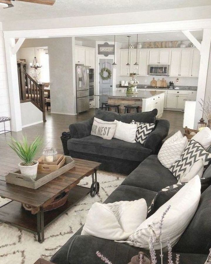 a living room filled with black couches and white pillows