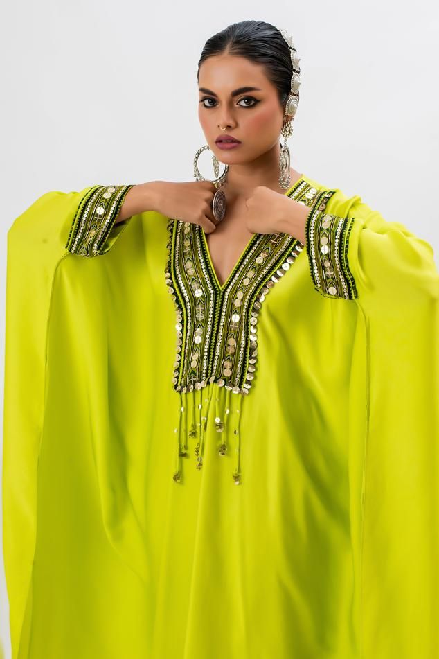 Neon green kaftan kurta with hand embroidered ajrakh border lace on yoke in front. Paired with stitched wrap skirt.
Components: 2
Pattern: Embroidered
Type Of Work: Ajrakh, Sequin, Zari, Thread
Neckline: V Neck
Sleeve Type: Batwing
Fabric: Satin
Color: Green
Other Details: 
Tassel details
Asymmetric hem
Occasion: Mehendi and Haldi - Aza Fashions Traditional Green Abaya With Dabka Work, Traditional Embellished Kaftan For Ceremonies, Bohemian Kaftan For Eid Ceremonies, Green Kaftan With Mirror Work For Navratri, Green Dabka Work Abaya For Eid, Green Traditional Drape Kaftan For Eid, Traditional Green Kaftan For Eid, Green Bohemian Kaftan For Traditional Ceremonies, Bollywood Style Kaftan With Traditional Patterns For Eid