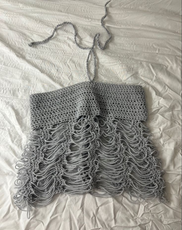 two crocheted pieces of clothing laying on top of a bed