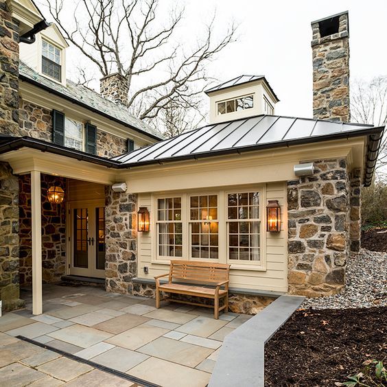 a stone house with a bench in front of it and lights on the side door