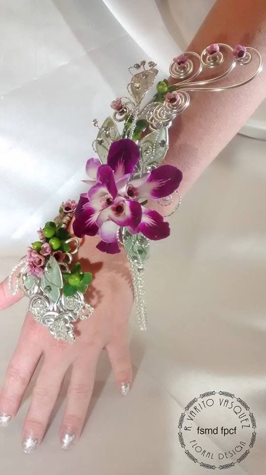 a woman's hand with purple flowers on it and silver jewelry attached to the wrist