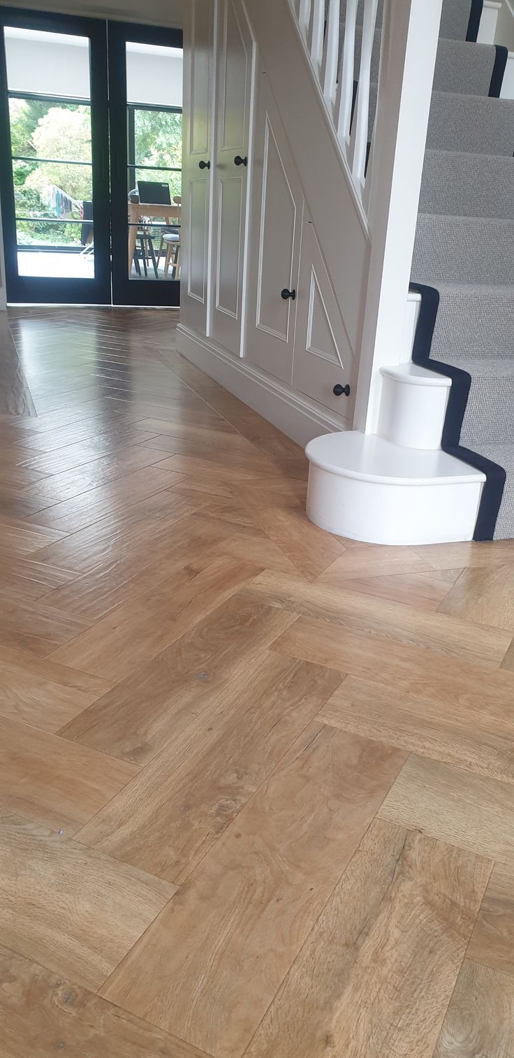 a wooden floor with white stairs and black doors in the background on a sunny day