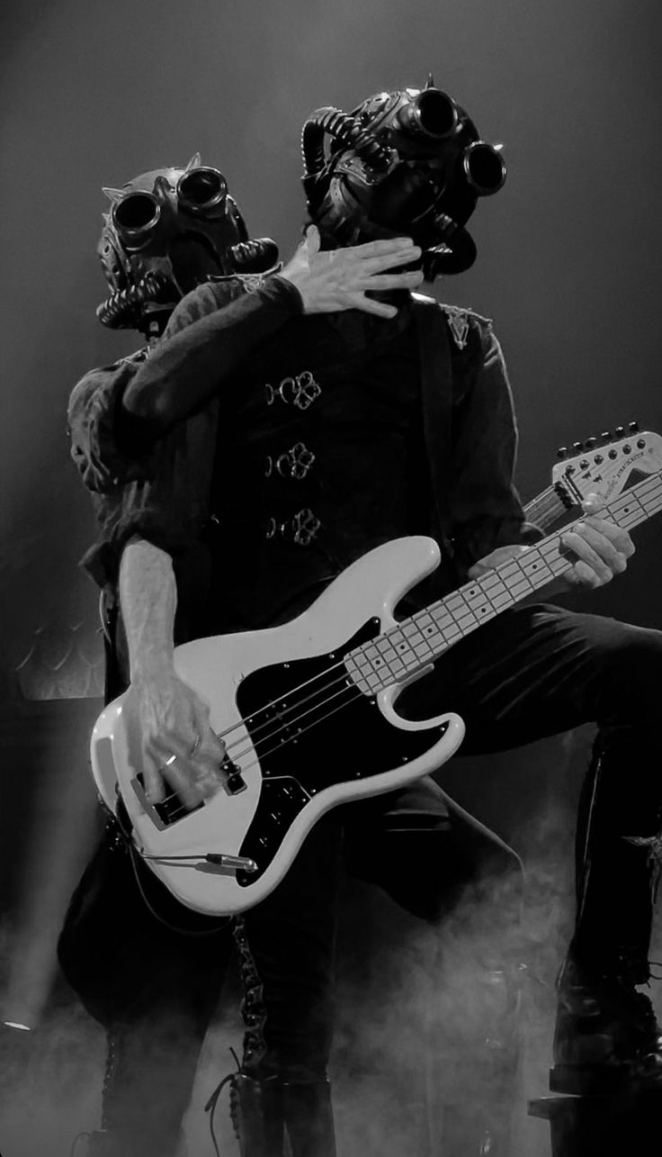 two men in gas masks are playing guitars