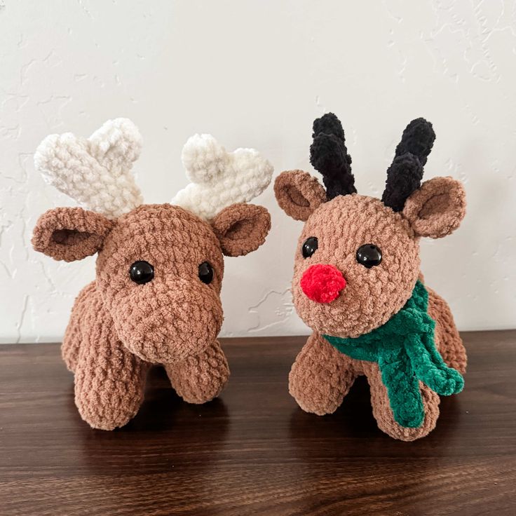 two crocheted reindeers sitting on top of a wooden table next to each other