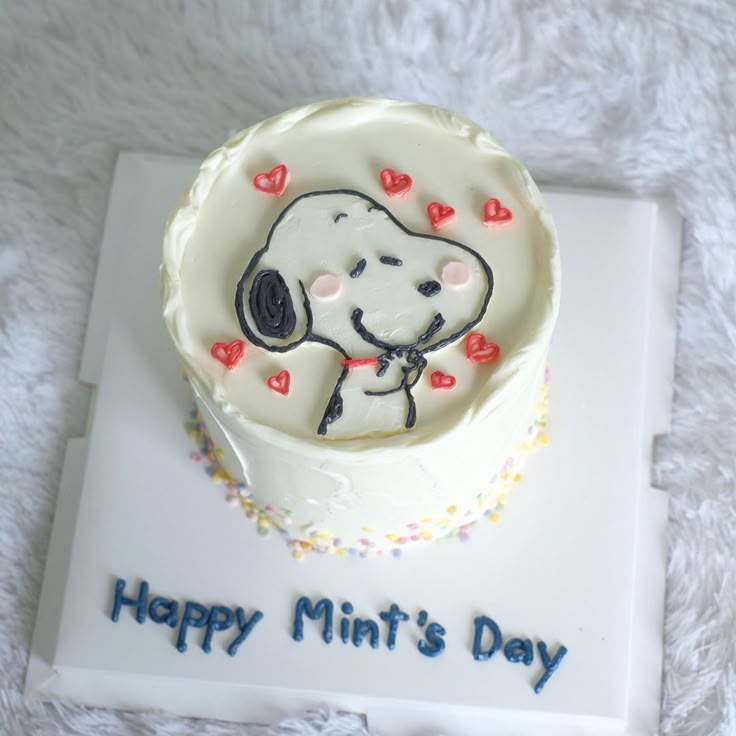 a white cake with a snoopy dog on it's frosting and the words happy mint's day