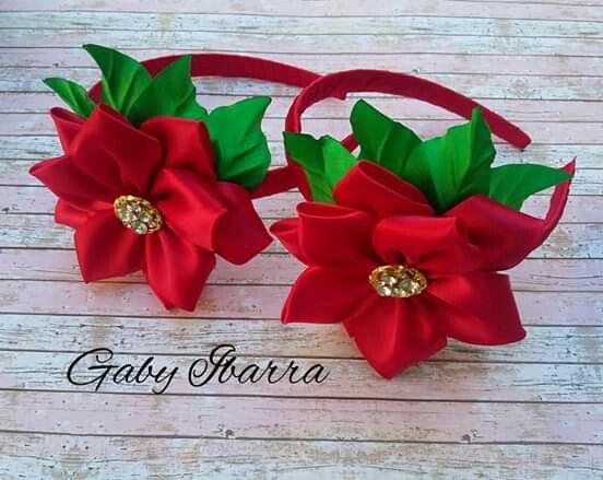 two red poinsettias with green leaves and gold centers on a headband