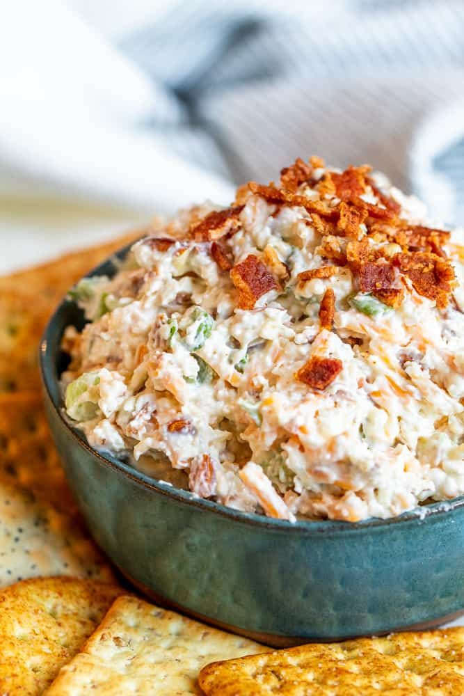 a blue bowl filled with coleslaw and crackers on top of a table