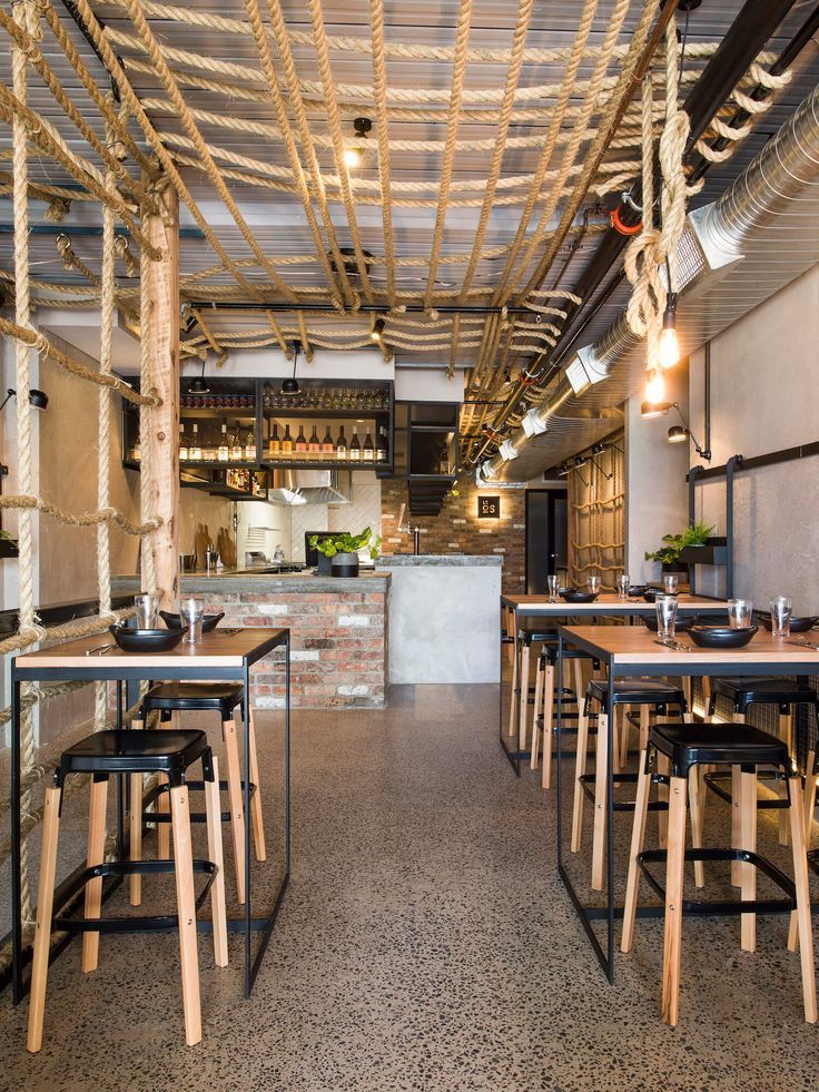 the interior of a restaurant with tables and stools in front of an open kitchen