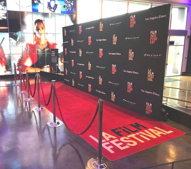 the red carpet is in front of a large screen with an image of a woman on it