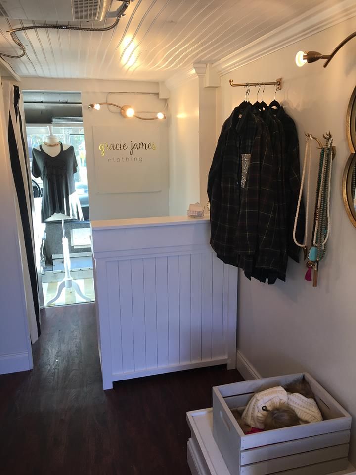 the inside of a clothing store with clothes hanging up