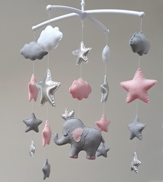 an elephant and stars mobile hanging from a white ceiling fixture with pink and grey decorations