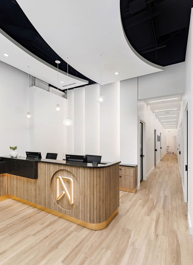 an office with white walls and wooden floors, along with black counter tops on either side of the desk