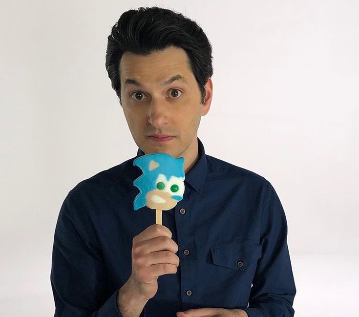 a man holding a blue and white cake popper in front of his face while looking at the camera