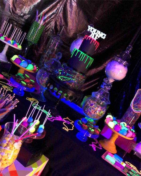 the table is full of candy and decorations for an event or party with neon colors