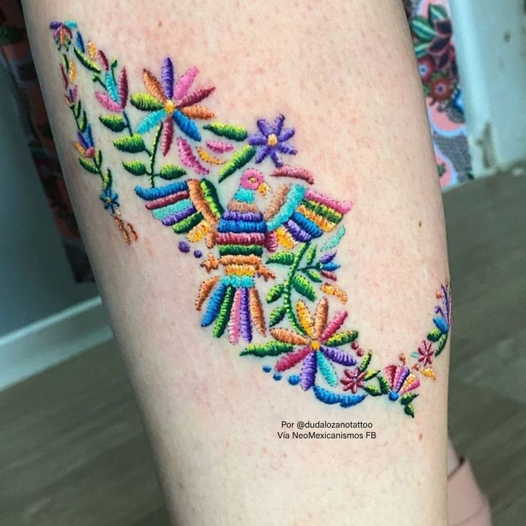 a woman's leg with colorful stitchs on it and a tattoo design in the middle