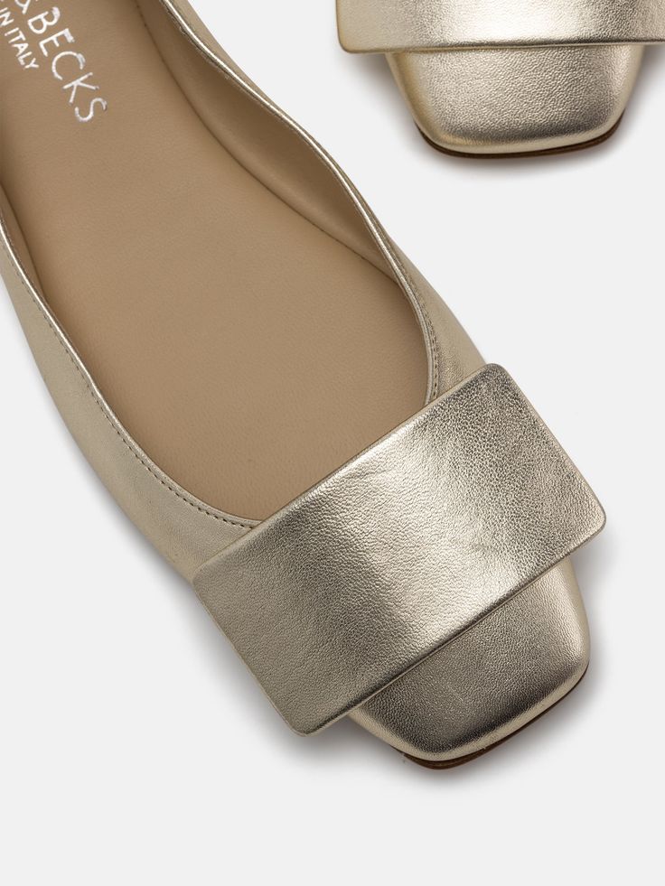 a pair of metallic shoes on top of a white surface