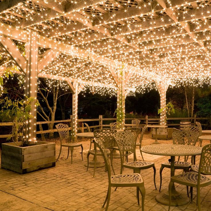 an outdoor dining area with tables and chairs covered in fairy lights for $ 9 99