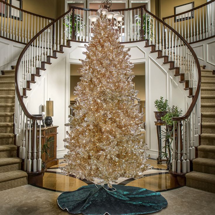 a large white christmas tree sitting in the middle of a living room next to stairs