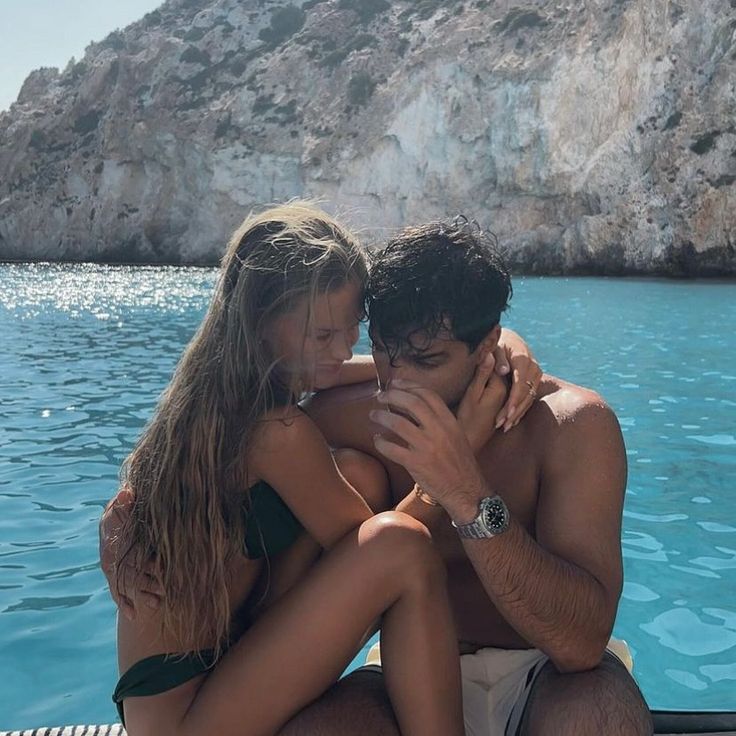 a man and woman sitting next to each other on a boat in the middle of water