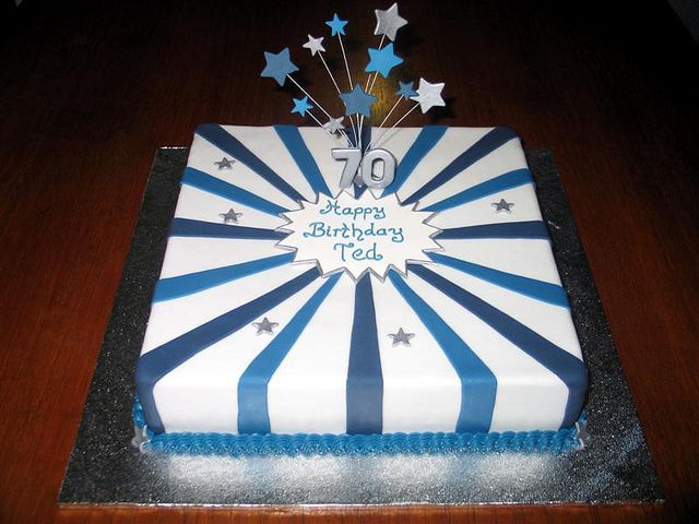 a blue and white birthday cake with stars on it's top is sitting on a wooden table