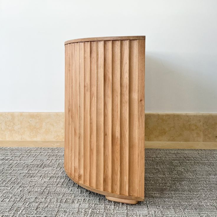 a wooden trash can sitting on top of a carpeted floor next to a wall