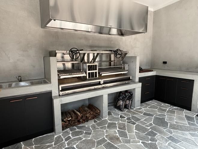 a kitchen with stone flooring and stainless steel stove top hood over it's range