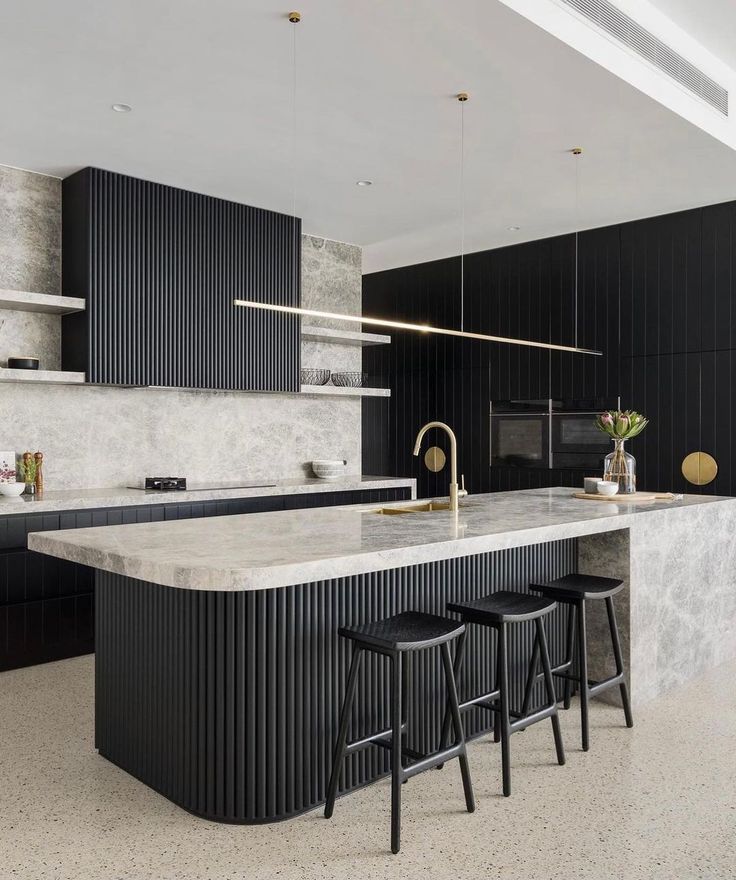 a kitchen with marble counter tops and black cabinets, along with two bar stools