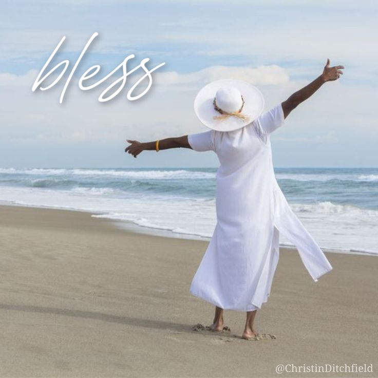 a woman standing on top of a beach next to the ocean with her arms outstretched