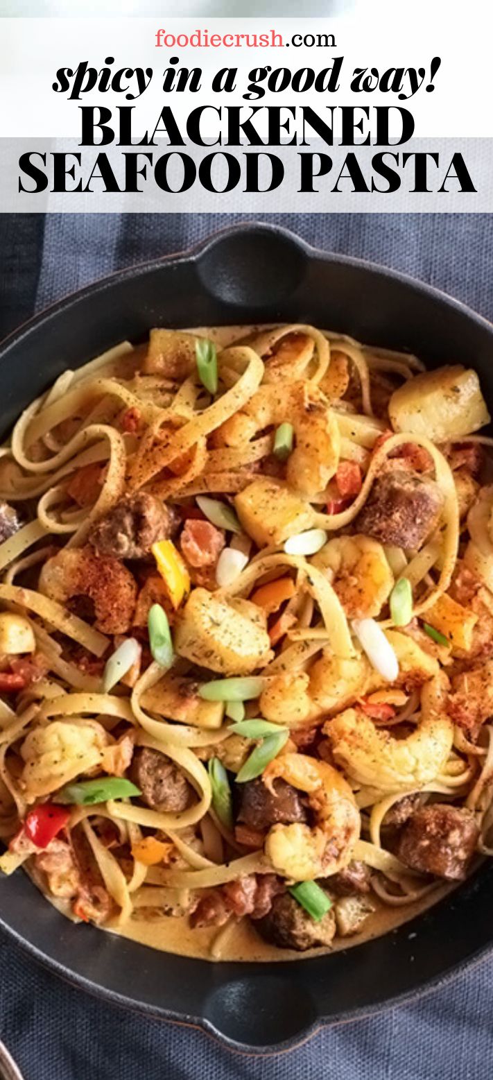 a skillet filled with pasta and meat on top of a blue cloth next to a fork