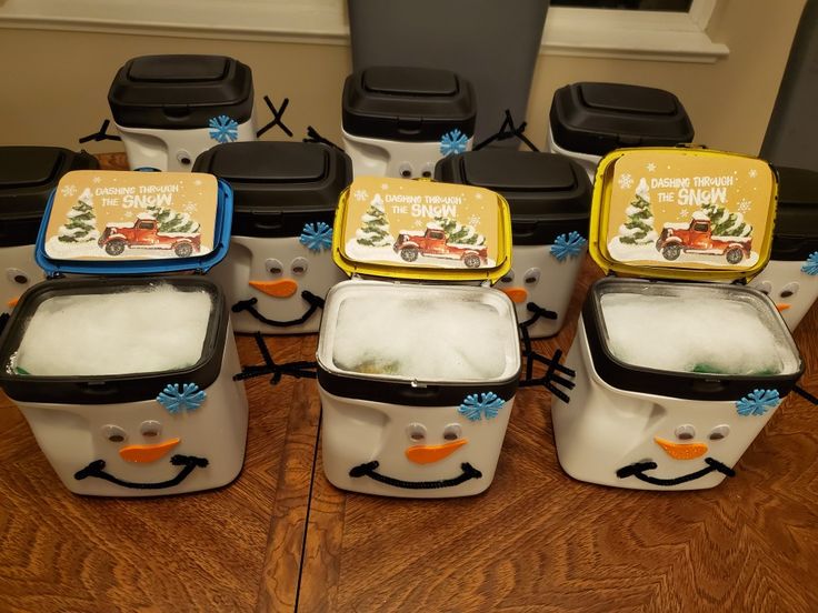 six small containers with snowman faces on them sitting on a wooden table in front of black chairs