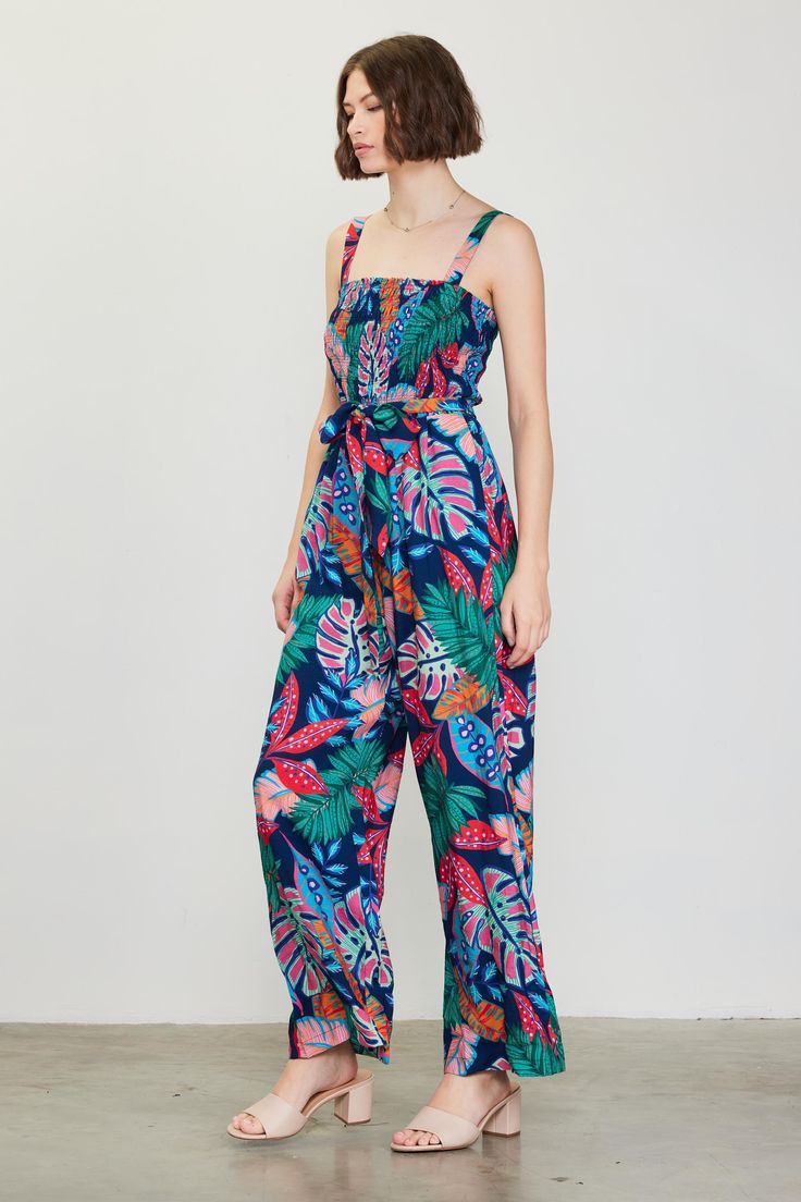 Fun, colorful, and impossible to ignore in a tropical floral print, this strappy jumpsuit is the ideal way to spice up your warm-weather wardrobe. It's got a smocked bodice that's balanced by a wide, roomy cut through the legs. A self-tie belt completes the look. "•Gathered shoulder straps •Smocked bodice •Ruffle trim at neckline •Optional self-tie belt •Wide-leg silhouette Item Number: 74403 SELF: 80% RAYON 20% NYLONE LINING: 100% RAYON Tropical Multicolor Jumpsuits And Rompers For Spring, Multicolor Tropical Jumpsuits And Rompers For Spring, Tropical Floral Print Jumpsuit For Vacation, Tropical Floral Print Jumpsuits And Rompers For Vacation, Sleeveless Smocked Bodice Jumpsuit For Vacation, Summer Multicolor Tropical Print Jumpsuits And Rompers, Tropical Multicolor Jumpsuits And Rompers For Vacation, Tropical Floral Print Sleeveless Jumpsuit, Tropical Sleeveless Floral Jumpsuits And Rompers