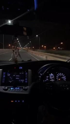 a car driving down the road at night with its lights on and it's dashboard illuminated