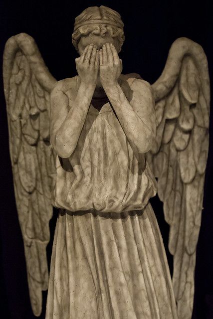 an angel statue covering its eyes with his hands