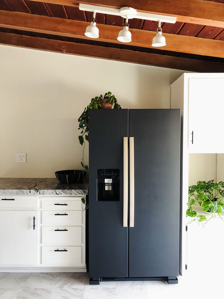 a black refrigerator freezer sitting inside of a kitchen next to white cabinets and drawers