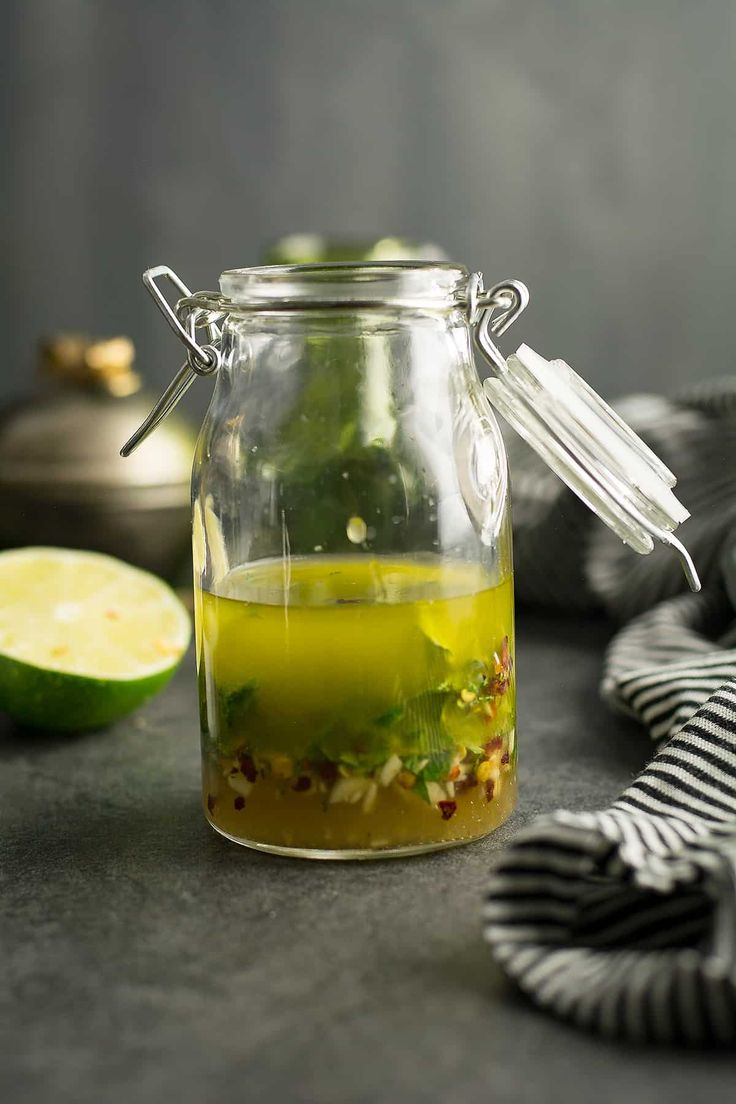 a glass jar filled with liquid next to sliced limes