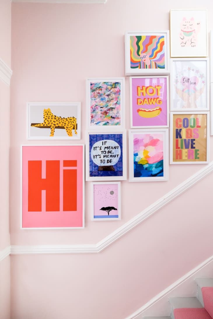 there are many pictures on the wall next to the stair case in this room with pink walls