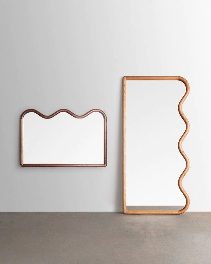 two mirrors on the wall next to each other and one is shaped like a wave