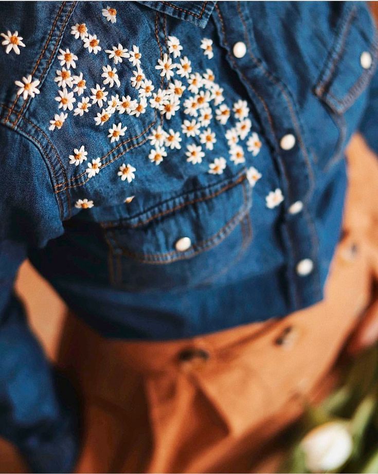 the back of a woman's jean jacket with daisies on it, and text that reads best hand made follow