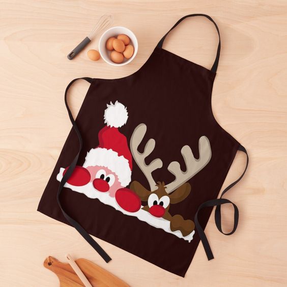 an apron with santa claus and reindeers on it next to utensils, eggs and spoons