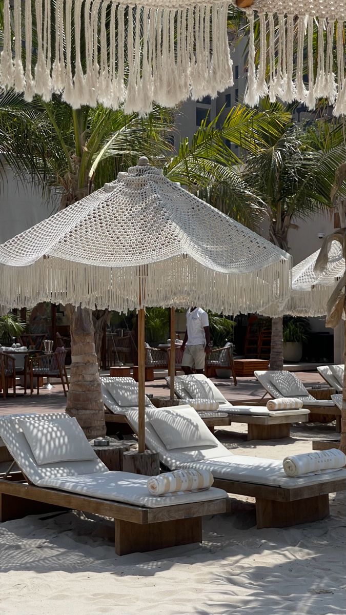 lounge chairs and umbrellas on the beach with palm trees in the backgroud