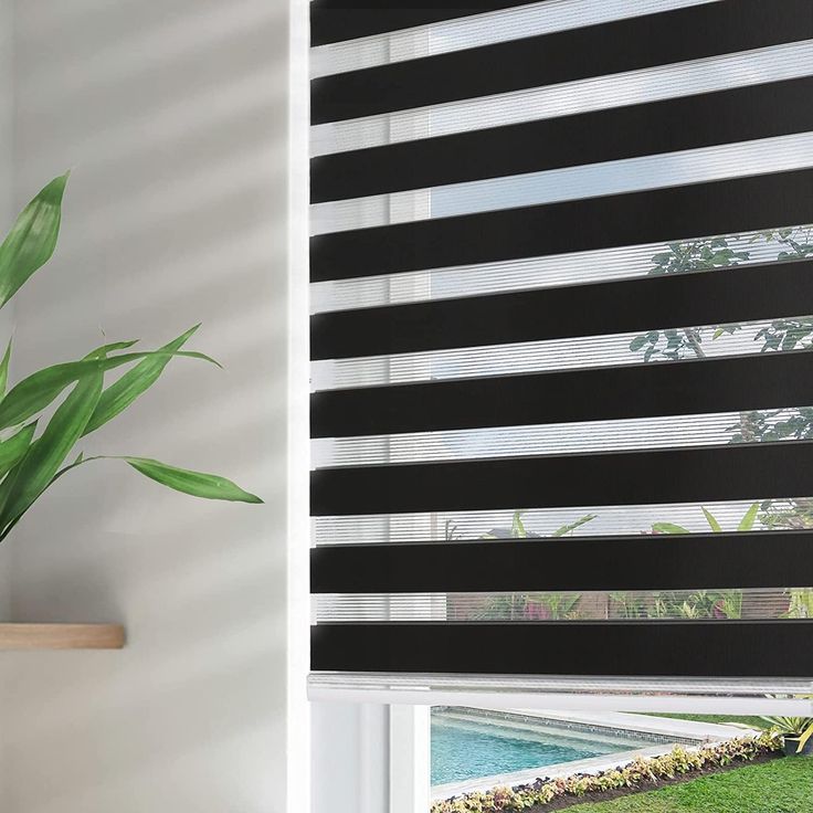 a black and white striped window blind next to a potted plant on a ledge