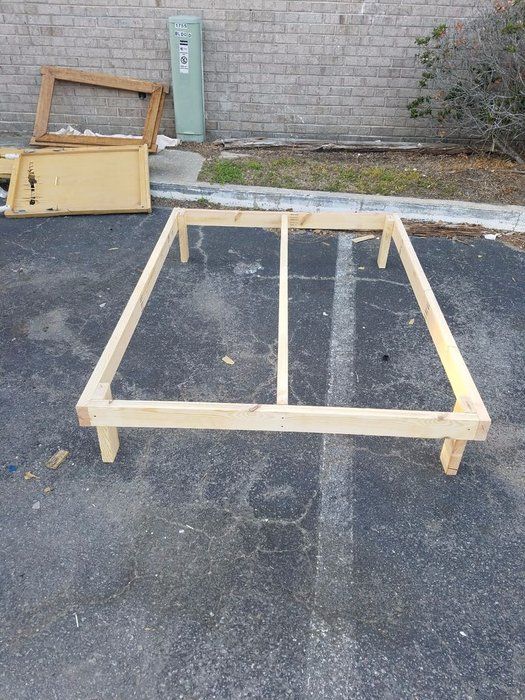 a wooden bed frame sitting on top of a parking lot