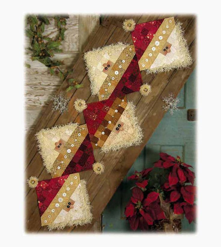 two christmas decorations on top of a wooden table next to a potted plant with poinsettis