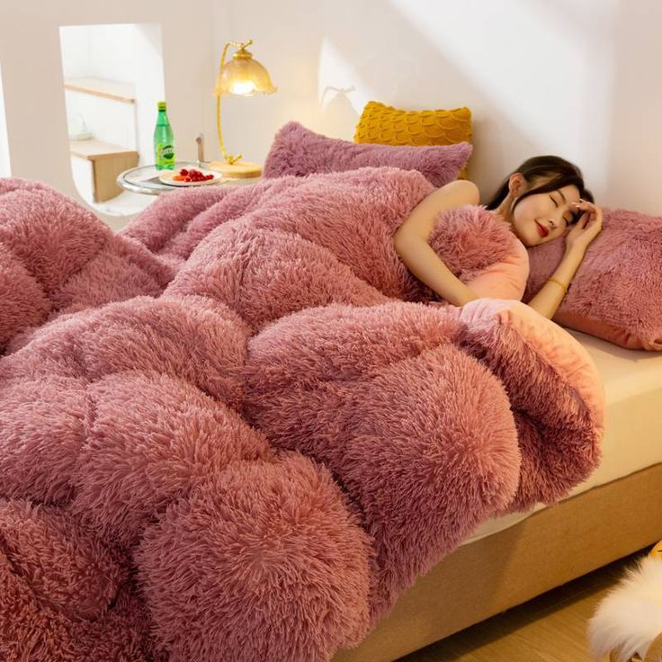 a woman laying on top of a bed covered in pink fluffy blankets