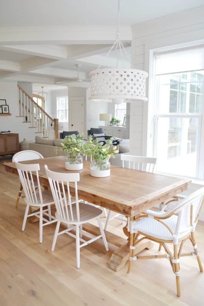 a dining room table with white chairs and a potted plant on top of it